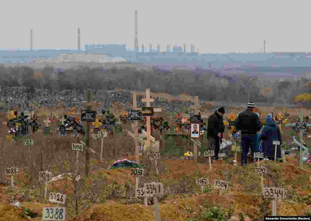 People visit a grave in the Mariupol cemetery on November 9. Tens of thousands of people are believed to have died during the nearly three-month-long siege of the city, during which civilians lived without power or water under nearly constant bombardment. 