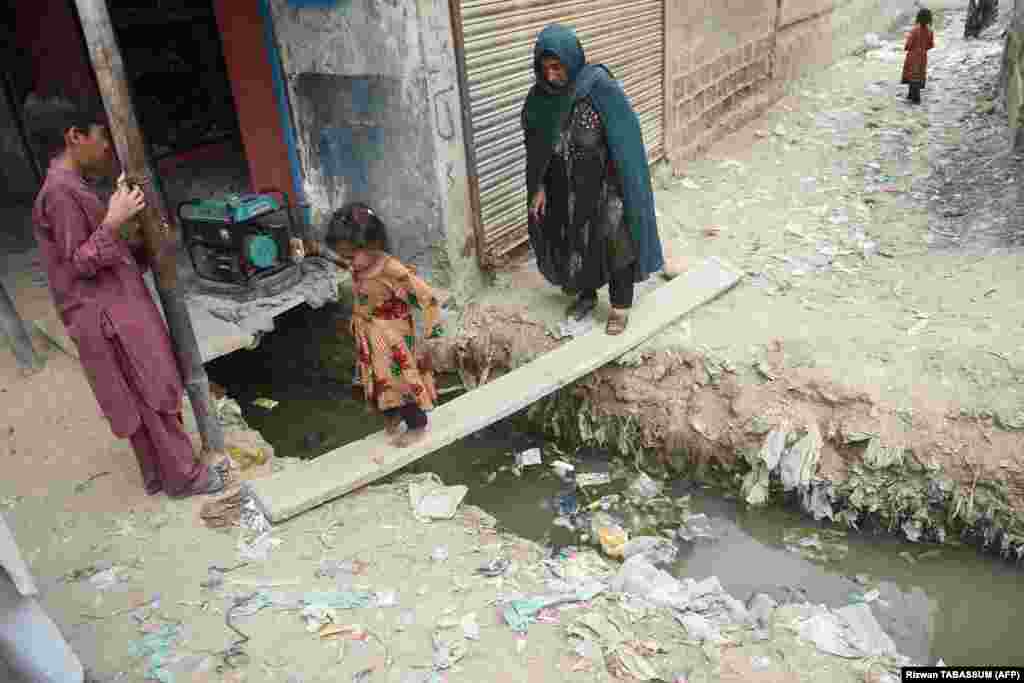 An Afghan girl and her mother cross an open sewer at a refugee camp in Karachi. Islamabad currently hosts about 1.4 million documented Afghan refugees. An equal number of undocumented Afghans are estimated to also be living in the country. &nbsp;