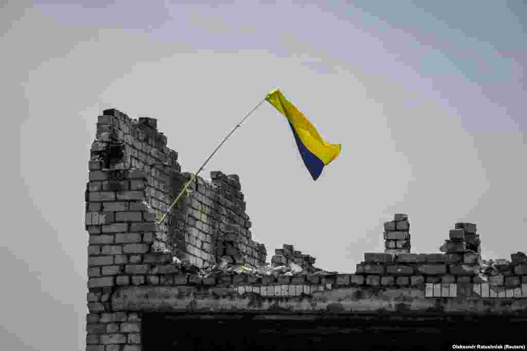 The Ukrainian national flag is seen above the rubble of a destroyed home in the newly liberated village of Neskuchne in the Donetsk region on June 13. Journalists were permitted entry to the village to show that Kyiv's forces have made gains in their counteroffensive against Russian forces.