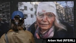 Një grua shikon një nga fotografitë e ekspozitës "Ukraina: Një krim lufte", që u hap në Prishtinë më 29 prill 2024. 