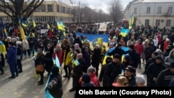 Demonstrators hold Ukrainian flags at a protest against the Russian occupation of Nova Kakhovka, Ukraine, on March 6, 2022