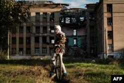 Девочка на фоне разрушенного обстрелами дома в Константиновке, 13 октября 2022 года