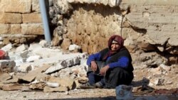 A woman rests near rubble in the Syrian town of Darat Izza in Aleppo Province on February 28.