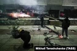 Протестующие запускают петарды в сторону полицейского спецназа возле парламента Грузии. 7 декабря 2024 года