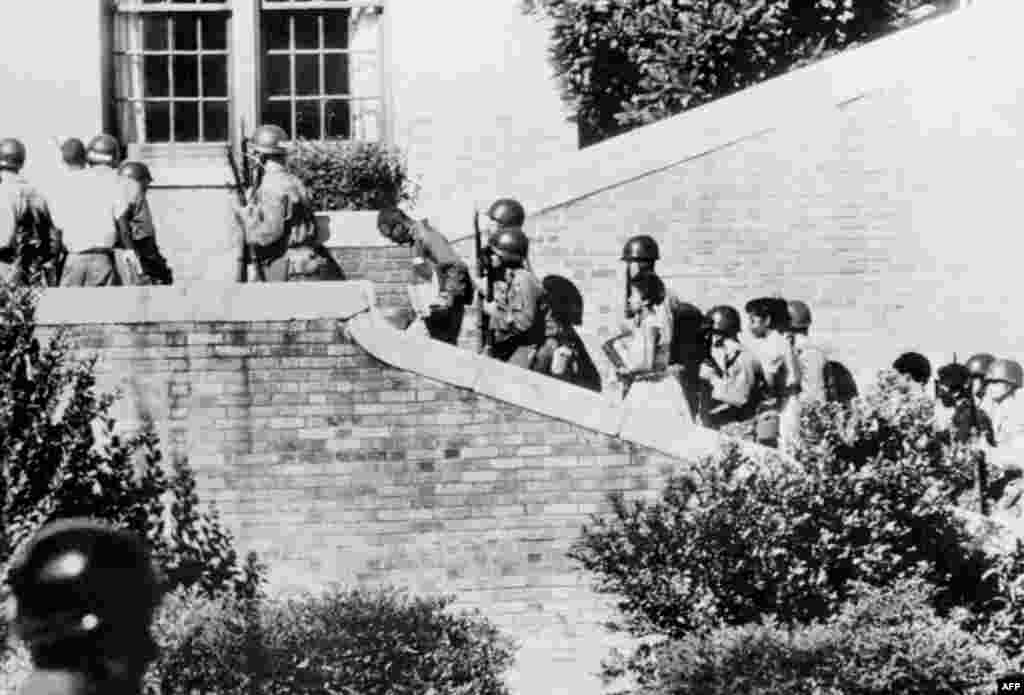 Nine black children are escorted by U.S. paratroopers outside a school in Little Rock, Arkansas, on September 25, 1957. U.S. President Dwight D. Eisenhower had ordered government troops to protect the children from angry protesters as they began attending a white-majority school. The state's governor, Orval Faubus, had ordered the state militia to bar the children from entering the school.