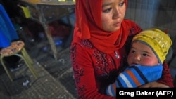 A Uyghur woman holds her baby in a night market in Hotan, in China's western Xinjiang region.