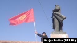 Човек мавта со киргистанско знаме покрај статуата на советскиот лидер Владимир Ленин во центарот на Ош. Градските власти ја симнаа статуата во јуни.