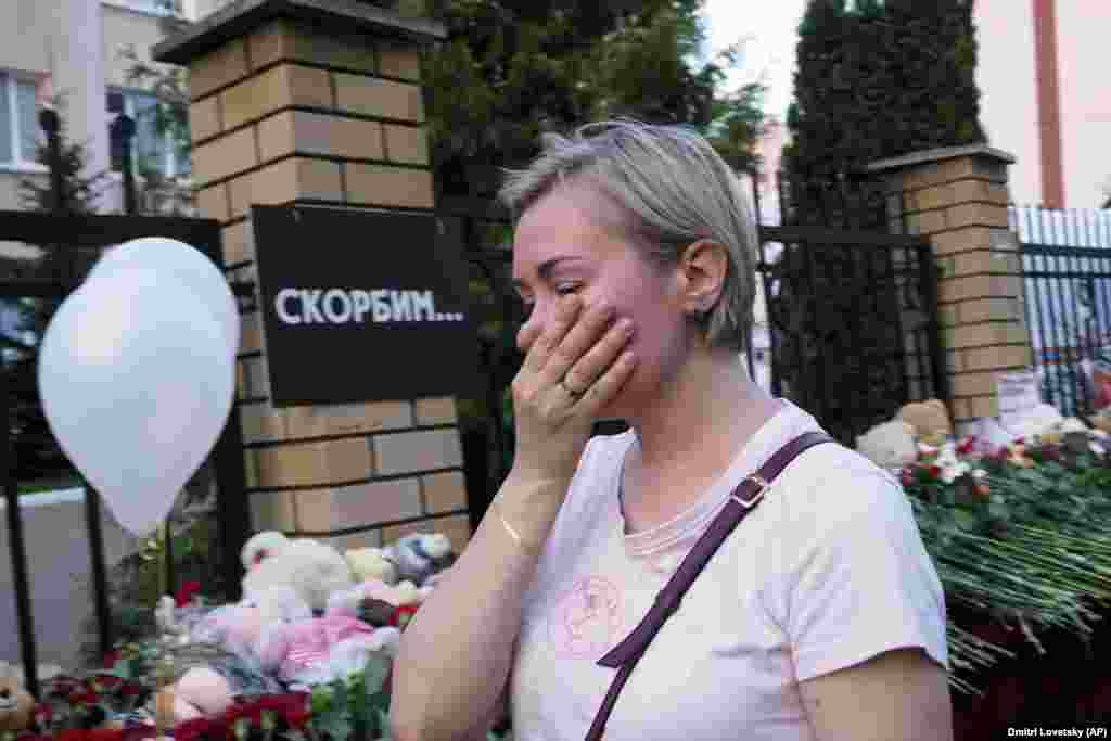 A woman cries near a school in Kazan on May 11. The writing on the wall reads, "We grieve."