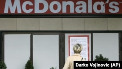 A woman reads a Latin-script sign at a McDonald's restaurant in downtown Belgrade. (file photo)