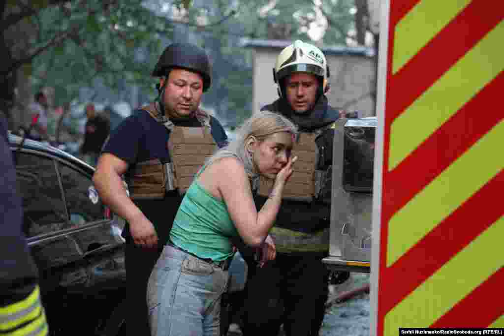 A survivor of a strike in Kyiv cleans herself alongside rescue workers.