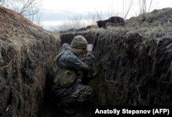 A cat looks down at a Ukrainian soldier resting in a trench on the front line with Russia-backed separatists near the village of Krasnohorivka in February.