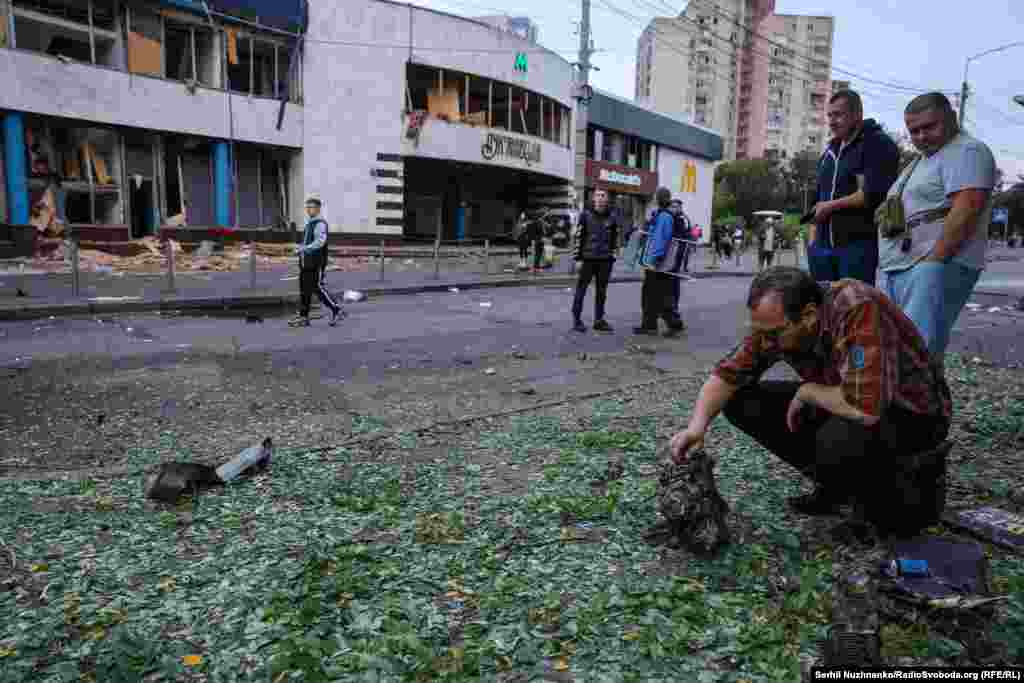 A man inspects a piece of engine after a night of Russian drone strikes in Kyiv on July 20-21. In the background is an entrance to the Lukyanivska subway station.