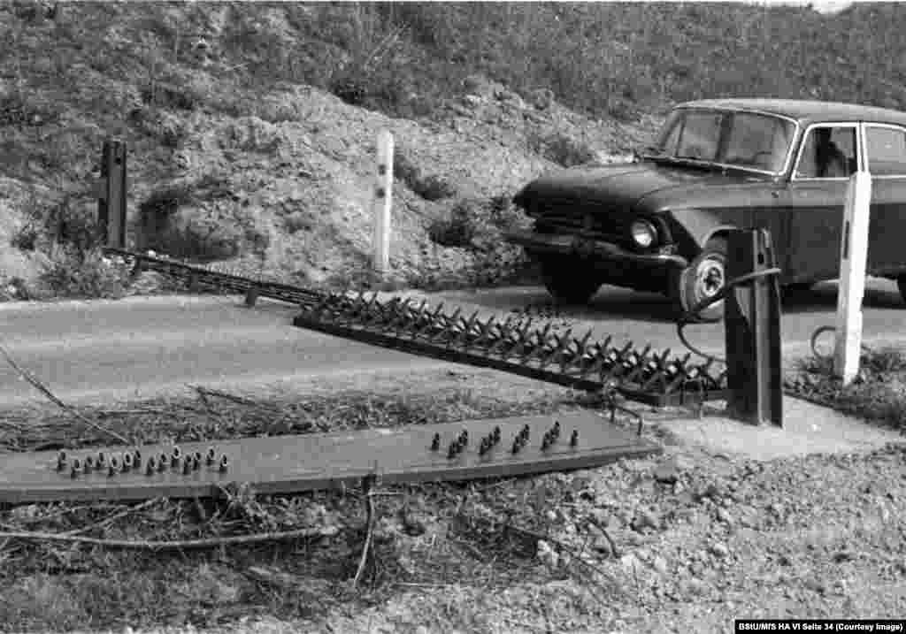 A car is driven towards a row of spikes as another tire-piercing plate awaits its trial at the Stasi's secret test facility in 1980. 