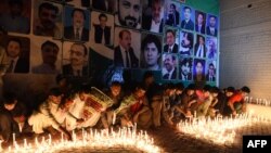 په کوټه کې یوشمېر کسانو پر دېوال د وژل شویو وکیلانو انځورونه ځړولي او په یاد کې یې شمعې بلوي - انځور له ارشیفه. 