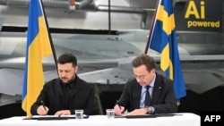 Prim-ministrul suedez Ulf Kristersson (R) și președintele ucrainean Volodimir Zelenski semnează o scrisoare de intenție pentru dezvoltarea capabilităților aeriene la Linköping, Suedia, pe 22 octombrie 2025.