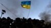 An antigovernment protester waves a Ukrainian flag behind a roadblock in Kyiv on January 27.